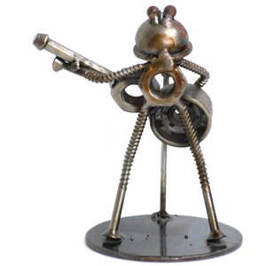 May include: A handcrafted metal sculpture of a musician playing a guitar. The figure is constructed from nuts, bolts, screws, and other hardware, with a round base. The sculpture has a rustic, industrial aesthetic.