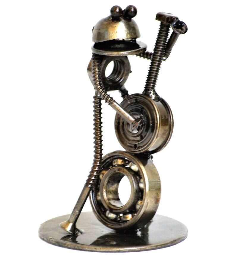 May include: A handcrafted metal sculpture of a musician playing a banjo. The sculpture is made from various metal hardware pieces, including nuts, bolts, and bearings. The banjo player is standing on a round metal base.