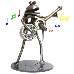 May include: A whimsical metal sculpture of a frog playing a musical instrument. The frog is constructed from various metal parts, including nuts, bolts, and bearings. Colorful musical notes and the word "La" are drawn around the frog.