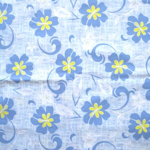 Puede incluir: Tela azul claro con un estampado floral repetitivo. El dise&ntilde;o presenta flores azules con centros amarillos, detalles blancos y l&iacute;neas azules onduladas sobre un fondo texturizado.