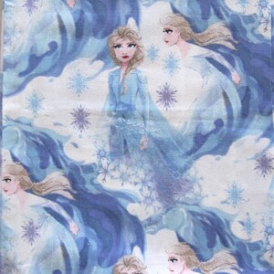 Puede incluir: Tela estampada con un dise&ntilde;o repetido de una mujer rubia con un vestido azul, rodeada de formas fluidas azules y blancas y copos de nieve. La mujer tiene una expresi&oacute;n seria y es el foco central del dise&ntilde;o. El fondo es azul claro y blanco.