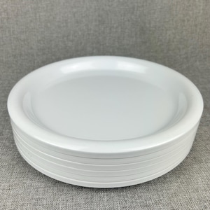 May include: A stack of white plastic dinner plates. The plates are round and have a slightly raised rim.