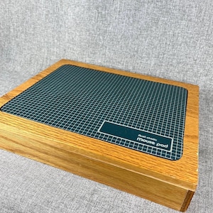 May include: A wooden mouse pad with a dark green surface and a white grid pattern. The pad has a rectangular shape and features the text "Anti-static mouse pad" in a white rectangular label.