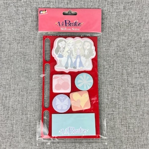 May include: A package of Lil Bratz stick-on notes featuring a large die-cut pad with four illustrated characters, plus smaller square and circular pads with cherry, starburst, butterfly, and heart designs, and a rectangular light blue note pad.