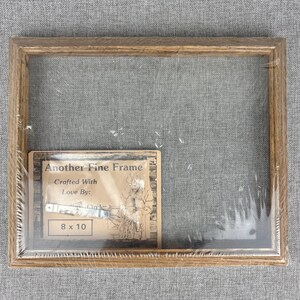 May include: A wooden picture frame with a clear plastic cover. The frame is 8x10 inches and has a label that says "Another Fine Frame" and "Crafted With Love By: Circle".
