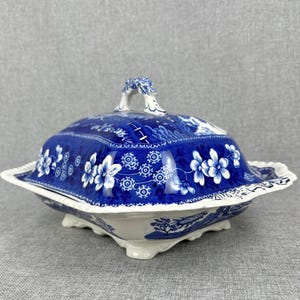 May include: A blue and white porcelain serving dish with a lid. The dish has a scalloped edge and a floral design. The lid has a handle in the shape of a bird.