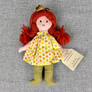 May include: A handmade doll with red yarn hair, a yellow and green polka dot dress, and green pants. The doll is holding a tag that reads "Little Brown House Originals by Pauline, Merrimack, N.H."