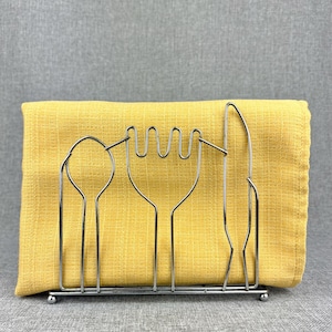 May include: A silver metal utensil holder with a yellow cloth napkin inside. The holder is shaped like a fork, spoon, and knife.