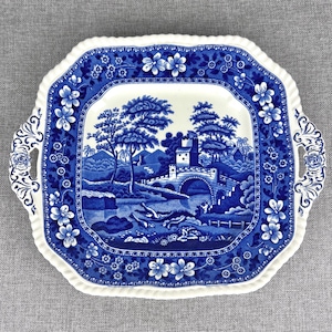 May include: A blue and white square serving platter with two handles. The platter features a blue and white landscape scene with a bridge, trees, and a small building.