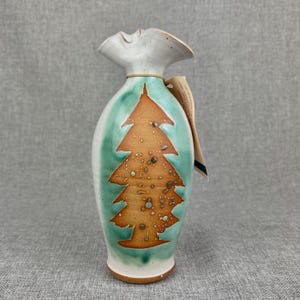 May include: A white ceramic vase with a green and brown glaze. The vase has a tree design with brown branches and a green background. The vase is about 10 inches tall.