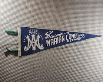 Könnte beinhalten: Eine marineblaue Wimpel mit weißem Text und Akzenten. Der Wimpel trägt die Aufschrift "Souvenir Marian Congress Ottawa" und zeigt ein stilisiertes "MA"-Monogramm. Grüne Bänder sind am Wimpel befestigt.