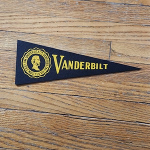 May include: Black felt pennant with gold lettering and a gold seal. The seal features a profile of a man and the text "Sigillum Universitatis Vanderbiltii MDCCCLXXiii". The pennant reads "VANDERBILT".