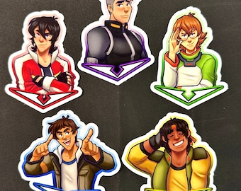 Pode incluir: Cinco adesivos coloridos com personagens de desenhos animados da série animada Voltron: Legendary Defender. Cada adesivo apresenta um personagem diferente com uma pose e uma expressão únicas. Os adesivos são impressos em um fundo branco com um contorno preto.