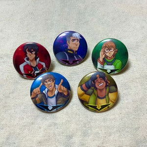 May include: Five round pinback buttons featuring characters from the animated series Voltron: Legendary Defender. The buttons are colourful and feature different characters from the show. The characters are depicted in a cartoon style and are wearing their signature outfits. The buttons are a great way to show your love for the show.