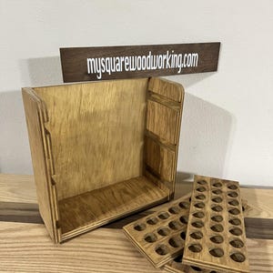 May include: A wooden storage box with a removable tray for holding small items. The box is made of light brown wood and has a natural finish. The tray has multiple circular cutouts for holding small items. The box is open and the tray is partially removed, revealing the interior of the box. The text "mysquarewoodworking.com" is visible on a small wooden sign.