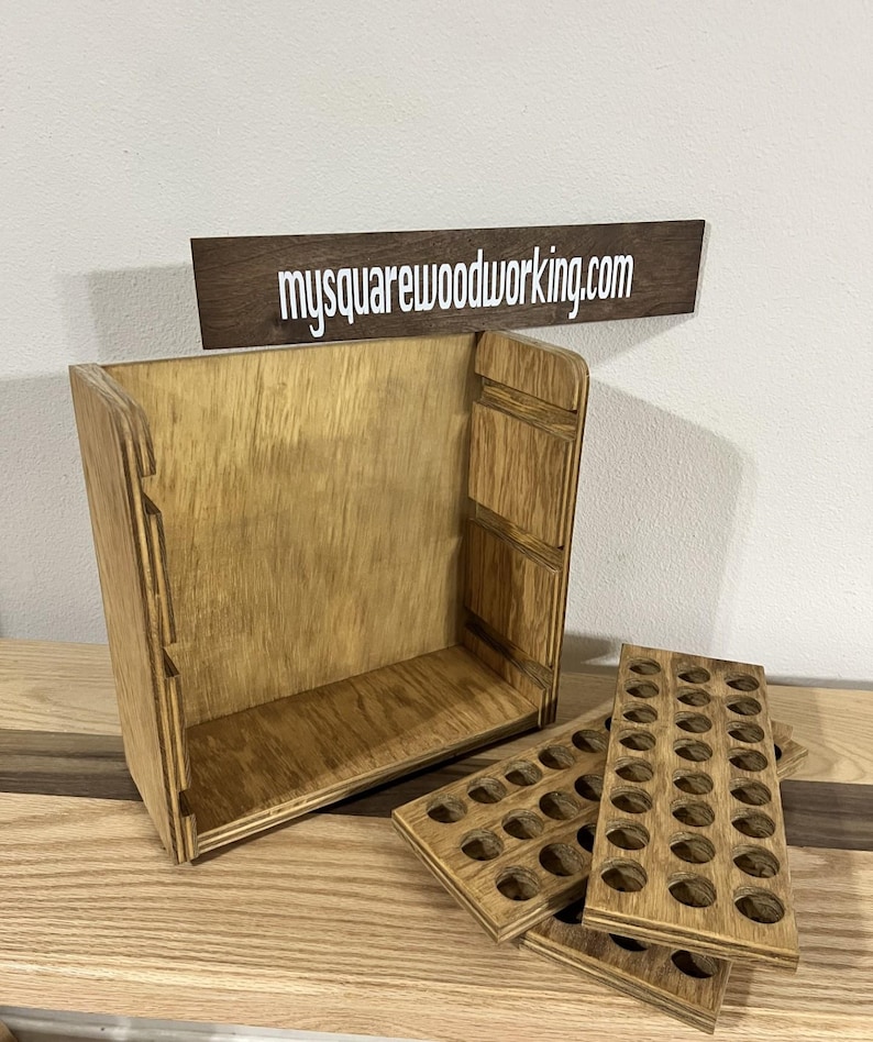 May include: A wooden storage box with a removable tray for holding small items. The box is made of light brown wood and has a natural finish. The tray has multiple circular cutouts for holding small items. The box is open and the tray is partially removed, revealing the interior of the box. The text "mysquarewoodworking.com" is visible on a small wooden sign.