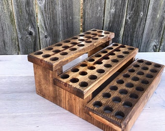 May include: A three-tiered wooden stand with circular holes for holding essential oils or other small items. The stand is made of natural wood with a dark brown stain.