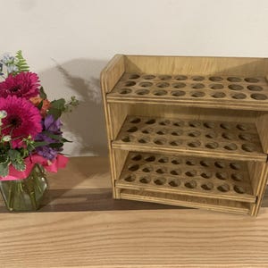 May include: Wooden storage shelf with three tiers of round holes, perfect for organizing small items like essential oils or craft supplies.