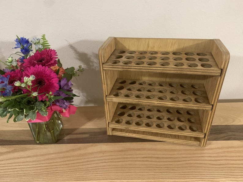 May include: Wooden storage shelf with three tiers of round holes, perfect for organizing small items like essential oils or craft supplies.