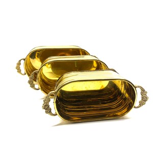 May include: Three gold oval-shaped planters with ornate handles. The planters are nested inside each other, with the largest planter at the bottom and the smallest planter at the top.