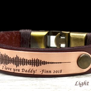 May include: A brown leather bracelet with a copper plate engraved with a sound wave and the text "I love you Daddy! - Finn 2018". Light Brown Leather.