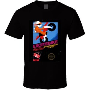 May include: Black t-shirt featuring a pixelated graphic of a motocross rider on a bike. The graphic includes the text "EXCITEBIKE" and "Nintendo Entertainment System" in red and white. The design is reminiscent of a classic video game.