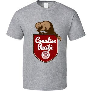 May include: A grey t-shirt featuring a vintage Canadian Pacific Railway logo. The logo depicts a beaver, a red shield with white text, and a globe with the text "Spans the World".