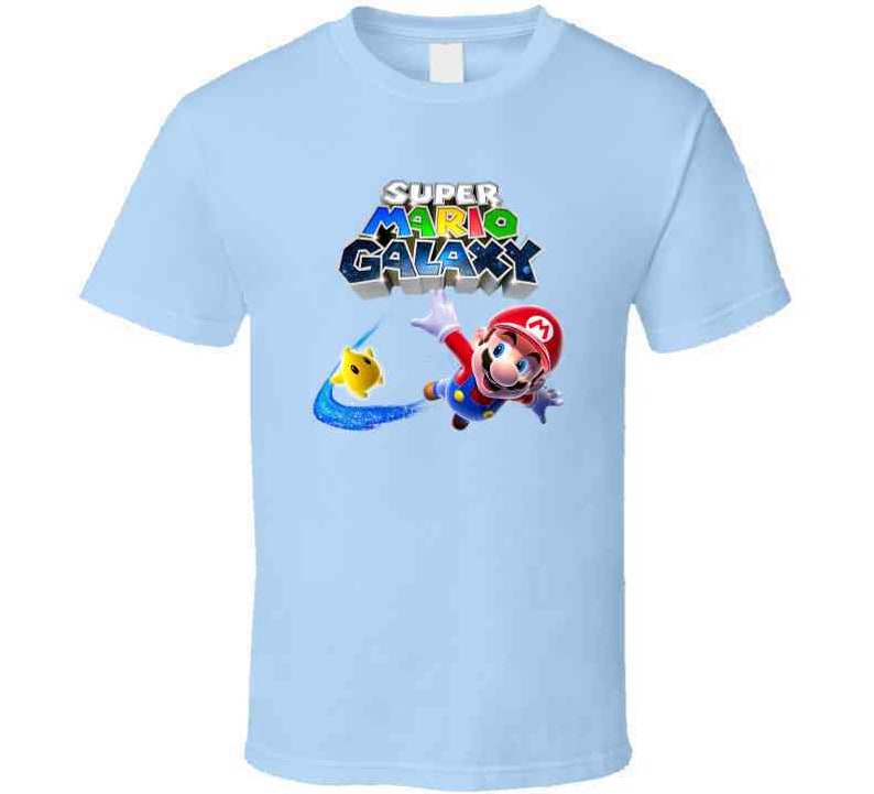 May include: Light blue t-shirt with a graphic of Mario from Super Mario Galaxy. The graphic features Mario in a red and blue suit, flying through the air with a yellow star. The text "Super Mario Galaxy" is printed in colorful letters above Mario.