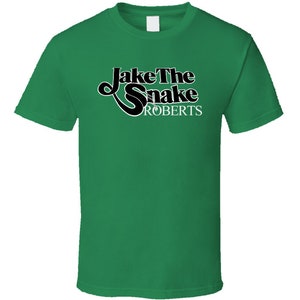 May include: A green t-shirt with a black and white graphic that says "Jake The Snake Roberts".