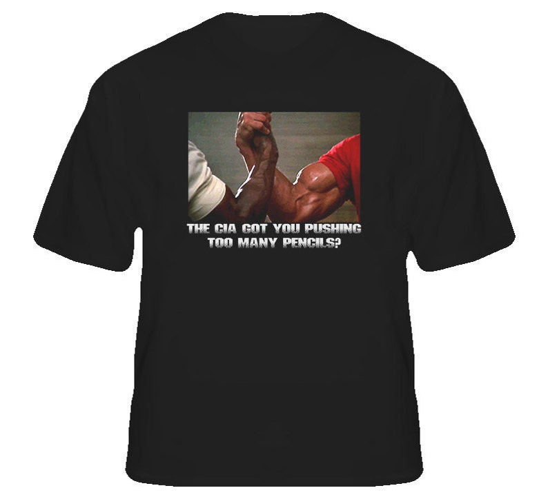 May include: Black t-shirt with a graphic of two muscular arms arm wrestling. The text on the shirt reads "The CIA got you pushing too many pencils?"