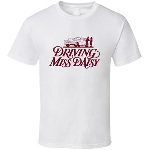 May include: White t-shirt with a burgundy print of a car and the text "Driving Miss Daisy".