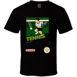 May include: Black t-shirt featuring a pixelated tennis game graphic. The design includes a tennis player, net, and the word "TENNIS" in green. The Nintendo logo is also visible.