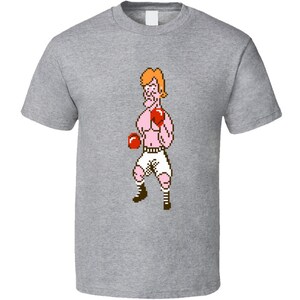 May include: A grey t-shirt with a pixelated image of a boxer wearing red boxing gloves and white shorts.
