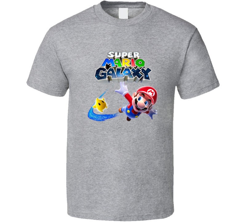 May include: A gray t-shirt with a graphic of Mario from Super Mario Galaxy. The graphic shows Mario flying through space with a yellow star. The text "Super Mario Galaxy" is printed above Mario.