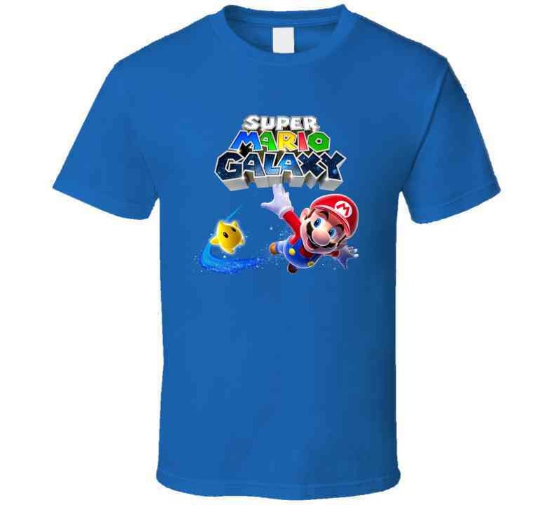 May include: A blue t-shirt with a graphic of Mario from the Super Mario Galaxy video game. The graphic features Mario in his signature red and blue outfit, holding a star and flying through the air. The text "Super Mario Galaxy" is printed in colorful letters above Mario.