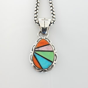 May include: A silver pendant necklace with a colorful, geometric design. The pendant features a teardrop shape with inlaid sections of orange, pink, green, and turquoise. The pendant is suspended from a silver chain.