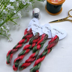 Pode incluir: Quatro carret&eacute;is de fio de bordar vermelho e verde com etiquetas que dizem "Ho! ho! ho!" e "220".