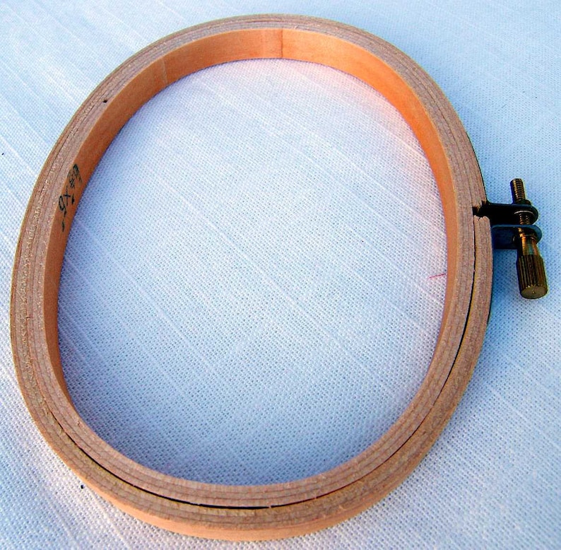 May include: A wooden embroidery hoop with a screw-on tightening mechanism. The hoop is 7 inches in diameter and is made of natural wood.