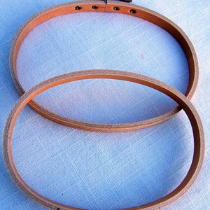 May include: Two wooden embroidery hoops, one nested inside the other. The larger hoop is 10 inches in diameter and the smaller hoop is 8 inches in diameter. Both hoops are made of natural wood and have a smooth finish.