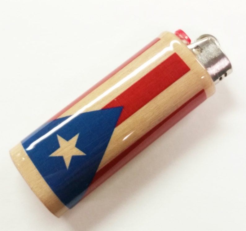 Peut inclure: Un briquet en bois avec un motif de drapeau portoricain rouge, blanc et bleu. Le briquet a un dessus argent&eacute; et un bouton rouge.