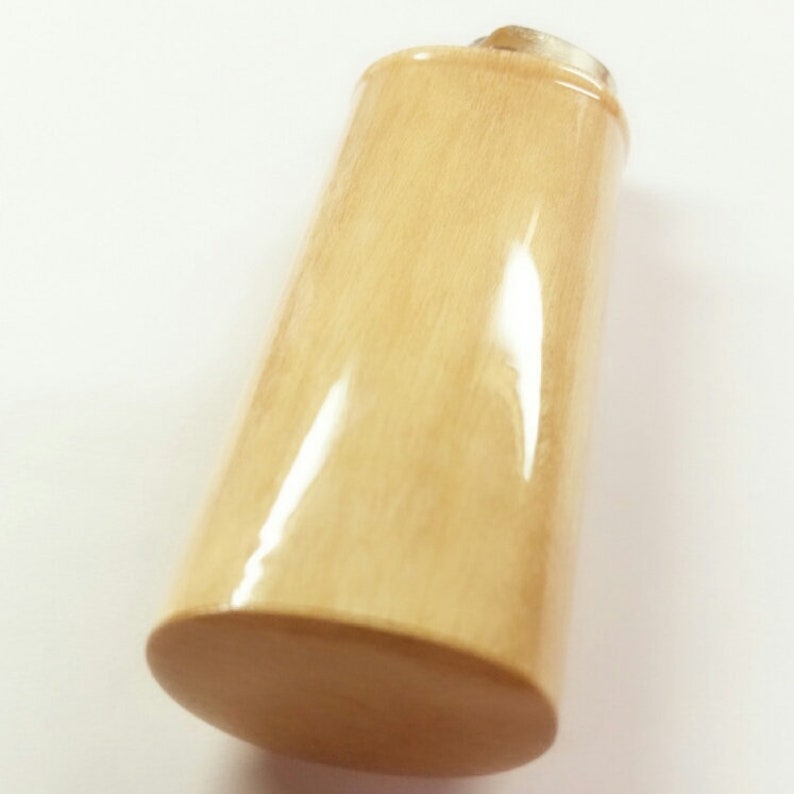 May include: A light beige bottle stopper made of wood with a smooth, polished finish.