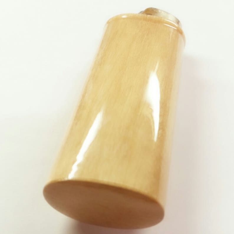 May include: A light beige bottle stopper made of wood with a smooth, polished finish.