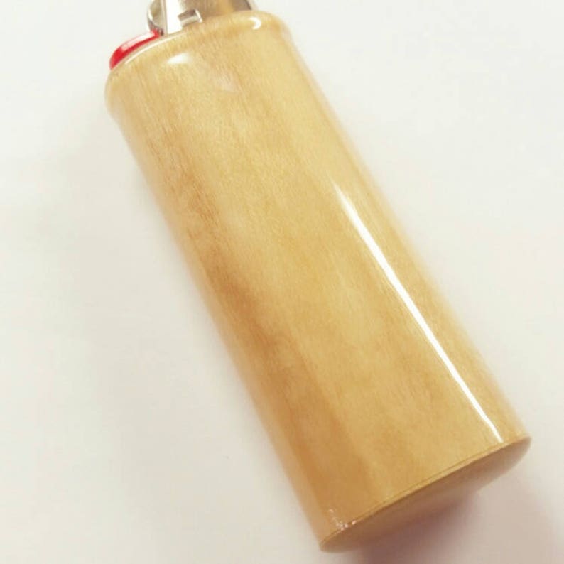 以下が含まれることがあります： 銀色のトップと赤いプラスチック製のインサートが付いた薄い茶色のライター。ライターは滑らかで光沢のある仕上げです。