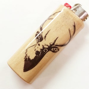 May include: A wooden lighter with a black and white deer design. The lighter is brown and has a silver top.