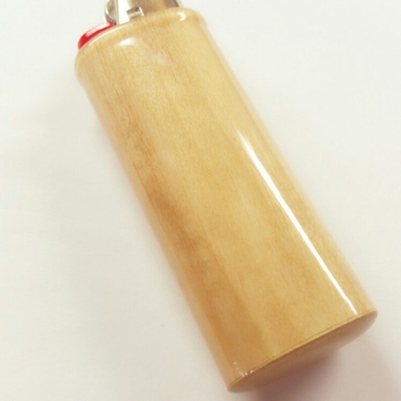May include: A wooden lighter with a light brown finish. The lighter has a silver top and a red bottom.