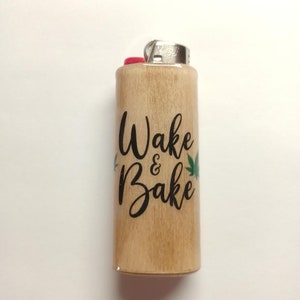 May include: A wooden lighter with a black and green design that says "Wake & Bake".