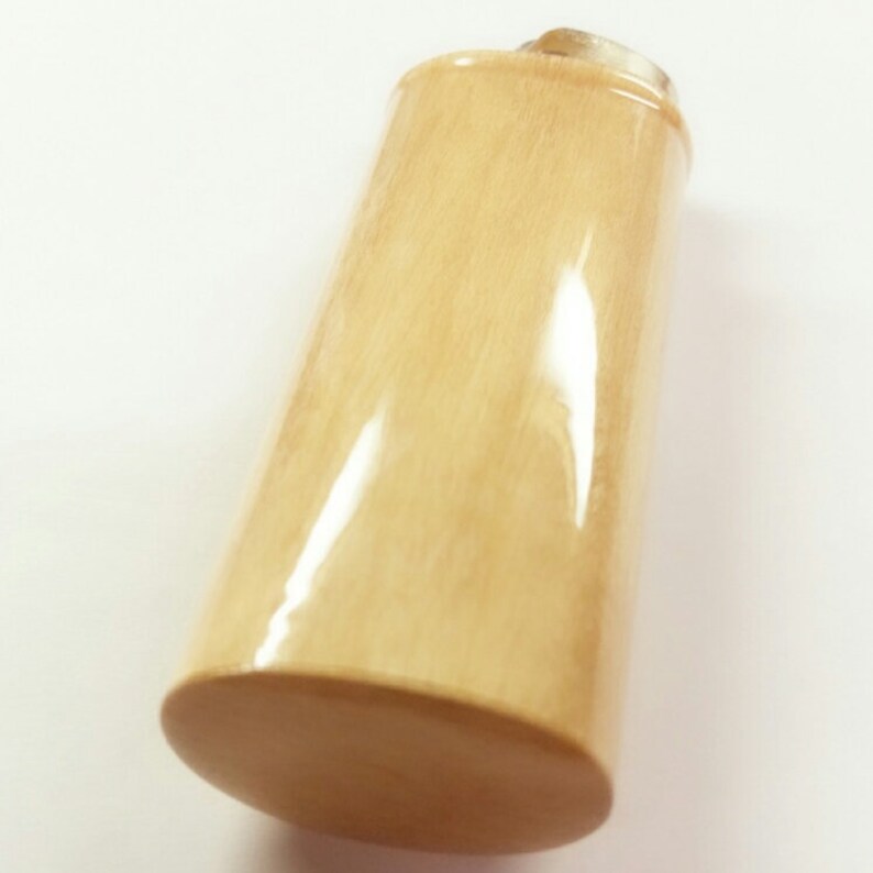 May include: A light beige bottle stopper made of wood with a smooth, polished finish.