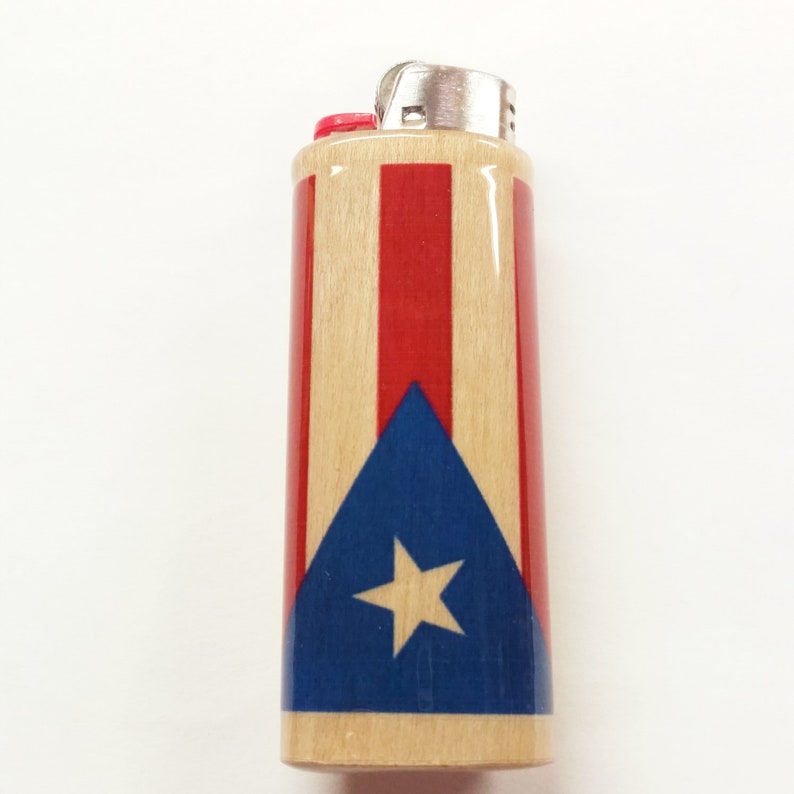 Peut inclure: Un briquet en bois avec un motif de drapeau portoricain rouge, blanc et bleu. Le briquet a un dessus argent&eacute; et un bouton rouge.