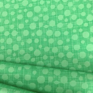 May include: Green fabric with a white polka dot pattern. The fabric has a subtle textured look.
