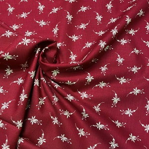May include: Burgundy fabric with a white floral pattern. The fabric is folded and has a soft, textured look.